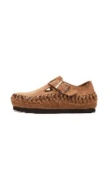 Zapato tipo zueco de cuero color beige, con diseño tejido artesanal en todo el contorno y ajuste mediante correa con hebilla metálica en el empeine.