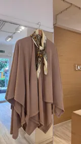 Ruana de tejido de punto fino en color beige, con diseño abierto y caída fluida.