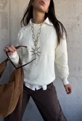 Sweater de punto color natural con diseño de flores bordadas en relieve, cuello redondo y puños acanalados. Presenta un corte clásico y versátil.