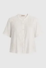 Camisa de lino color blanco, con cuello mao, manga corta y cierre frontal con botones. Cuenta con delicados detalles bordados tono sobre tono.