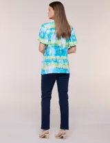 Blusa de rayón en tonos turquesa y verde, con cuello en V con detalles bordados, mangas cortas amplias y diseño estampado con motivos florales y geométricos.