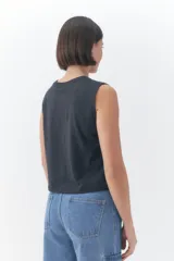 Musculosa Roxy modelo Line Up de color negro, con diseño sin mangas, cuello redondo y corte corto. Cuenta con un estampado frontal gráfico estilo vintage que incluye la palabra "Roxy", palmeras y un sol, acompañado del texto "sunsets chaser".