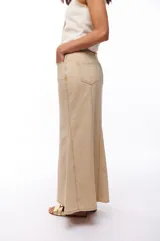 Falda larga de jean color beige, corte recto con vuelo en el ruedo y costuras verticales a lo largo de la prenda.
