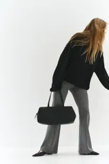 Pantalón de tiro alto con corte acampanado, confeccionado en tejido con patrón de espiga. Presenta cierre frontal oculto y bolsillos traseros insertados.