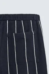 Pantalón de corte relajado, color azul marino, con rayas verticales blancas finas. Presenta cintura elástica ajustable con cordón interior y bolsillos laterales y traseros de plastrón.