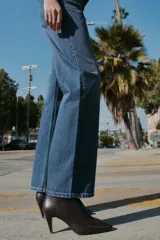 Jeans de tiro alto con diseño de cinco bolsillos, pernera recta y corte largo. Presenta cierre frontal con cremallera y botón metálico.