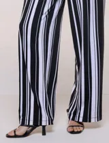 Enterito largo sin mangas con cuerpo negro de escote alto y pantalón wide leg de rayas verticales blancas y negras, con cintura elastizada y cordón ajustable.
