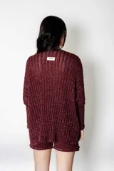 Poncho tejido en lurex color bordó, con textura acanalada y brillo. Presenta un calce suelto y relajado.