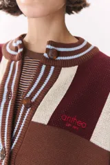 Cardigan de punto con diseño de bloques de color en tonos marrón, beige y verde. Presenta cuello redondo, cierre frontal con botones, mangas largas con hombros caídos y logo bordado en el frente.