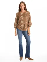 Blusa de tejido fino color marrón con bordado floral en hilo dorado. Presenta cuello redondo, mangas tres cuartos abullonadas con puños elásticos fruncidos y ruedo redondeado con corte asimétrico.