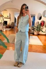 Chaleco de denim en tono claro, con escote redondo y cierre frontal de botones.