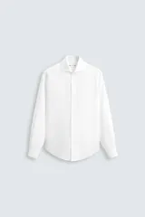Camisa blanca de manga larga con cuello italiano abierto y cierre frontal de botonadura.