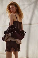 Vestido corto de satén fluido color marrón oscuro, con breteles finos ajustables, escote recto y detalles de encaje festoneado en el escote y en el ruedo.