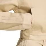 Campera corta Adidas Firebird color beige con cierre frontal y cuello alto. Presenta las tres líneas características de la marca en las mangas.