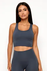 Conjunto deportivo de dos piezas en color gris oscuro, compuesto por un top de tirantes anchos con escote redondo y largo extendido con recortes en la cintura, y una calza de tiro alto con costuras modeladoras.