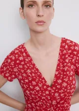 Vestido midi rojo con estampado floral blanco, cuello en V, manga corta y detalle de nudo frontal en el pecho.