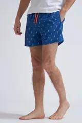 Short de baño para hombre, color azul vibrante, con estampado repetitivo de arabescos en blanco. Presenta cordón de ajuste naranja en la cintura.