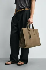 Bolso tipo bandolera de piel con acabado abatanado, diseño rectangular con doble asa de mano y detalle de llavero colgante. Cuenta con compartimento principal con cierre de mosquetón y bolsillo interior con cremallera.
