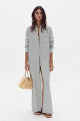 Vestido largo camisero de lino a rayas celestes y blancas, con cuello camisero, mangas largas, bolsillo aplicado en el pecho y cierre frontal con botones.