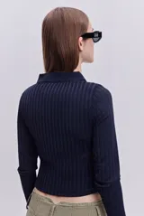 Top de calce al cuerpo confeccionado en tejido elástico con textura acanalada. Presenta cuello camisero, mangas largas y un recorte frontal tipo cut out.