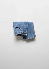 Pantalón jeans de tiro alto estilo mom-fit, color azul con lavado clásico, diseño de cinco bolsillos y cierre frontal con cremallera y botón metálico.