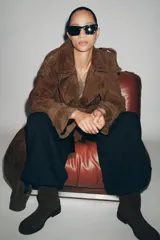 Botín plano de mujer confeccionado en serraje color marrón oscuro, con caña baja, tirador trasero y cierre mediante cremallera lateral. Presenta punta redonda y suela plana.