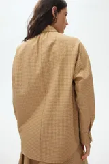 Camisa de corte relajado en tejido dobby con estampado de cuadros, cuello con detalle de moña y botonadura frontal. Presenta hombros caídos y mangas largas con puños abotonados.