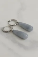 Aros tipo argolla de acero quirúrgico con dije colgante en forma de gota de piedra natural en tono marrón.