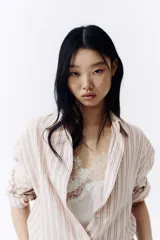 Camisa de corte oversize, con diseño de rayas verticales en tonos rosados, blancos y beiges, cuello clásico, mangas largas con puños abotonados y cierre frontal de botones.