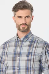 Camisa de manga larga con estampado de cuadros en tonos azules, grises y marrones. Presenta cuello abotonado, bolsillo frontal en el pecho y botones personalizados.