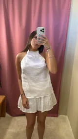 Minifalda blanca acampanada de lino, tiro medio/alto y cierre invisible en la espalda.