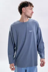 Remera de manga larga en color azul piedra, con corte holgado y cuello redondo. Presenta una pequeña estampa minimalista en el pecho con el texto 'MODERN ease'.