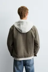 Sobrecamisa de denim de algodón negro con efecto lavado, corte relajado (relaxed fit). Presenta cuello solapa, cierre frontal con cremallera, manga larga con puño abotonado y bolsillo plastrón en el pecho.