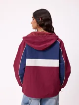 Campera rompevientos Rusty con diseño color block en tonos bordó, azul y blanco. Cuenta con cierre frontal, capucha con cordones ajustables, puños elásticos y logo bordado en el pecho.