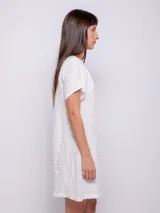 Vestido corto de corte holgado, color celeste, con cuello redondo fruncido y mangas cortas. Está confeccionado en una tela con textura diferenciada que le aporta relieve.