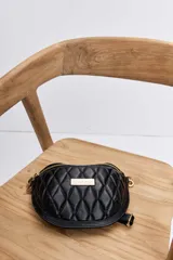 Riñonera Urban Haus de diseño acolchado con patrón de rombos, color negro, con cierre superior y placa metálica dorada con el logo de la marca en el frente.