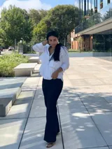 Camisa azul marino de manga larga con cuello camisero y cierre de botones. Presenta volantes horizontales en la parte delantera.