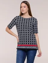 Remera de algodón con estampado geométrico en blanco y negro, de manga corta, con detalle de guarda roja y flecos en el ruedo.