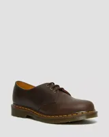 Zapato de tres ojales Dr. Martens modelo 1461, confeccionado en cuero Crazy Horse de color marrón con acabado encerado. Presenta costuras amarillas visibles en el borde de la suela y suela de goma con cámara de aire.