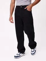 Jean de corte slouchy, color negro, con diseño de cinco bolsillos y cierre frontal con botón y cremallera.