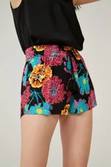 Short negro con estampado de flores en tonos rosa, naranja, amarillo y celeste. Tiene cintura elastizada con cordón de ajuste y detalle de borlas en los extremos.