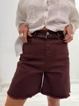 Bermuda color borgoña de gabardina elastizada, corte a la rodilla, con cinto fino con tachas y detalles de flecos en el ruedo.