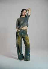 Pantalón wide leg de mujer con pierna amplia, diseño de efecto desgastado con tonos amarillos y verdes, y detalles rotos.