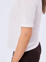 Remera blanca de manga corta 100% algodón, con delicado bordado frontal de diseño botánico y detalles calados en las terminaciones de las mangas.