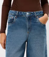 Pantalón de jean estilo wide leg con cintura media, cierre frontal con botón y bolsillos funcionales. Presenta un diseño de corte amplio y recto, con bordado de estrellas en los bolsillos traseros.