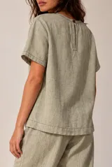 Blusa de lino color beige, de manga corta y cuello redondo, con detalles de bordados geométricos en contraste.
