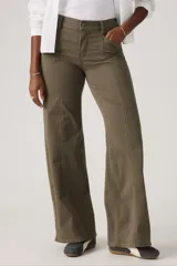 Pantalón de jean estilo wide leg en color verde oliva, con costuras verticales frontales que recorren el largo de las piernas. Presenta un diseño de tiro medio con cierre de botón y cremallera, y bolsillos laterales.