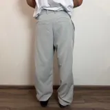 Pantalon sastrero de corte baggy, color gris claro, con pinzas en la cintura y cierre frontal.