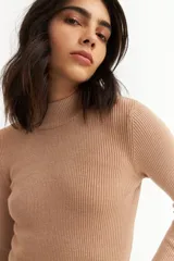 Polera de tejido de punto color beige con brillo metalizado, cuello alto y mangas largas.