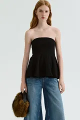 Top strapless de punto con escote recto y diseño ajustado en el torso, que finaliza en un peplum acampanado. Cuenta con una banda de silicona interna en el borde superior para mayor sujeción.